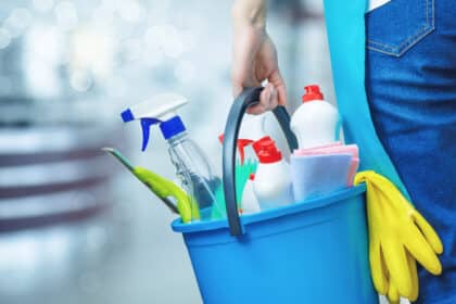 Eimer mit Reinigungsmitteln, Sprühflasche, Handschuhen und Putzutensilien in der Hand einer Person – Symbolbild für Haushalt, Putzen, Reinigungstipps oder Frühjahrsputz