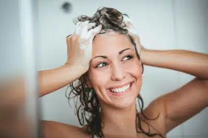Lächelnde Frau beim Haarewaschen unter der Dusche