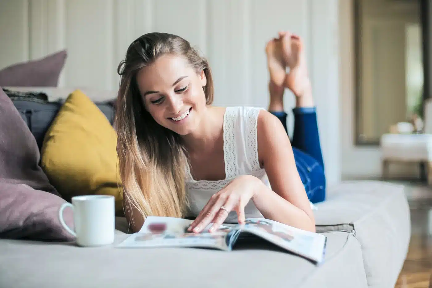 Frau entspannt auf dem Sofa mit Kaffee und Zeitschrift