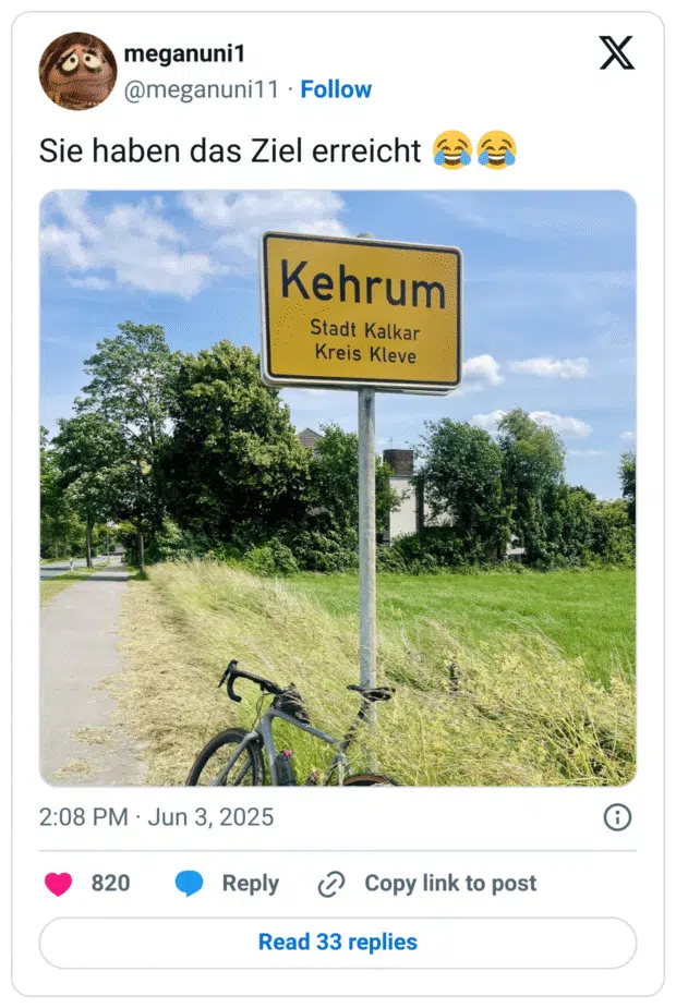 Ortsschild mit der Aufschrift „Kehrum – Stadt Kalkar, Kreis Kleve“. Davor steht ein Fahrrad auf einem Feldweg. Der humorvolle Kontext ergibt sich aus dem Wortspiel „Sie haben das Ziel erreicht“, da „Kehrum“ wie „Kehr um“ klingt – als würde das Navi nach der Ankunft zur Umkehr auffordern.