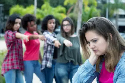 Trauriges Mädchen wird von einer Gruppe Gleichaltriger ausgegrenzt – Mobbing unter Jugendlichen im Alltag