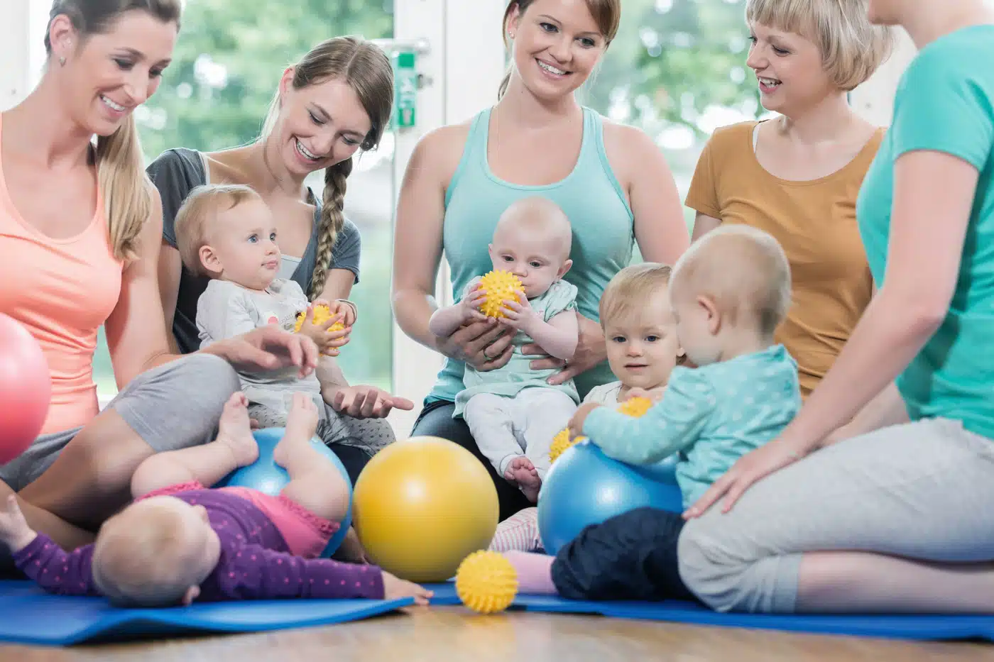 Mütter mit Babys beim Eltern-Kind-Kurs oder der Krabbelgruppe in heller Umgebung – Symbolbild für Frühförderung, Gemeinschaft und Elternzeit