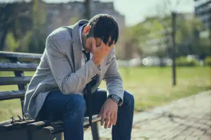 Ein junger Geschäftsmann sitzt auf einer Bank und hat einen mentalen Zusammenbruch.