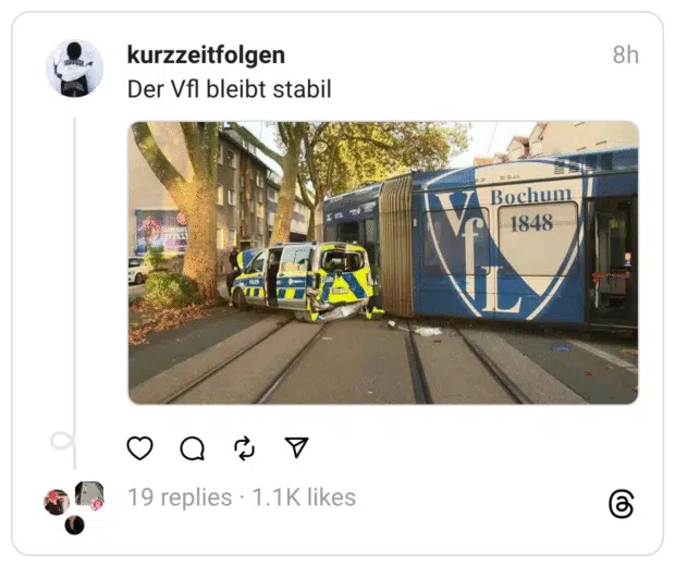 Ein Polizeiauto ist seitlich stark beschädigt, nachdem es offenbar von einer Straßenbahn gerammt wurde. Die Bahn trägt groß das Logo und den Schriftzug „VfL Bochum 1848“. Dazu steht als ironischer Kommentar: „Der VfL bleibt stabil“. Die Szene spielt sich auf Straßenbahnschienen in einer Stadtstraße ab, umgeben von Bäumen und Häusern.