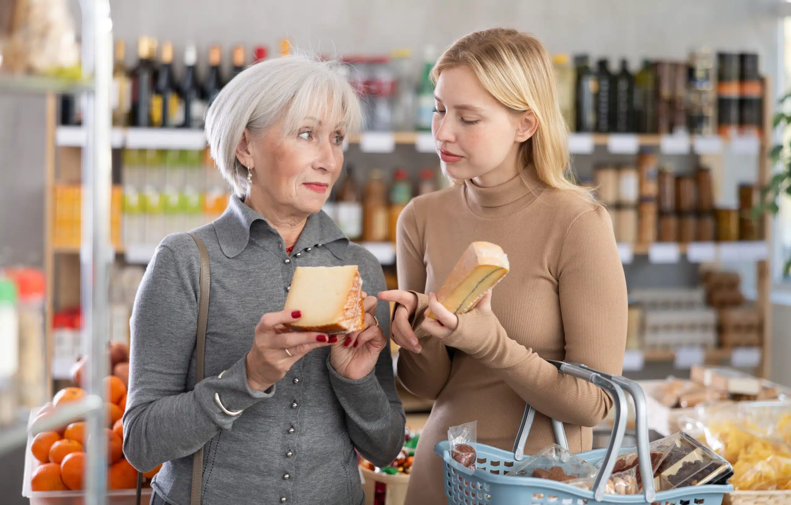 Ältere Frau und junge Frau sind einkaufen und zeigen empört auf den Käse.