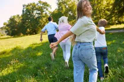 Glückliche Familie rennt gemeinsam über eine sonnige Wiese – Symbolbild für Ausflüge, Zusammenhalt, Familienzeit und Naturerlebnis.