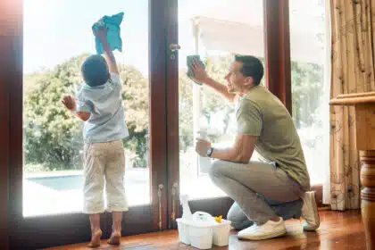 Ein kleiner Junge hilft seinem Vater beim Fensterputzen – Teamwork im Familienalltag