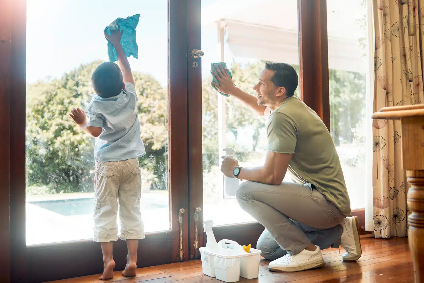 Ein kleiner Junge hilft seinem Vater beim Fensterputzen – Teamwork im Familienalltag