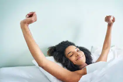 Frau liegt entspannt im Bett und streckt sich am Sonntagmorgen – Symbolbild für Entspannung, Selbstfürsorge oder Morgenroutine.