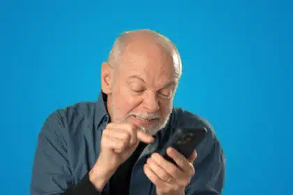 Älterer Mann schaut genervt auf sein Smartphone und tippt frustriert – Symbolbild für Technikprobleme oder digitale Überforderung.