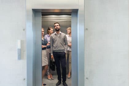 Mehrere Personen stehen im Aufzug und warten darauf, dass sich die Tür schließt.