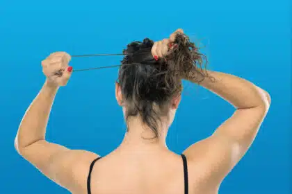 Frau bindet sich mit einem Haargummi die Haare zu einem Zopf.