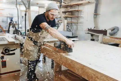 Handwerker arbeitet in der Werkstatt mit Schleifmaschine an Holz.