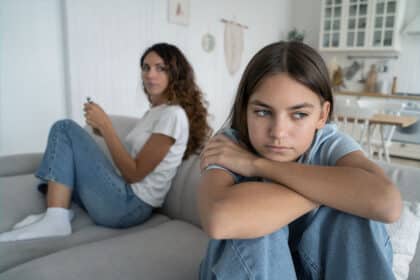 Mutter und Tochter sitzen distanziert auf dem Sofa und haben sich gerade gestritten.