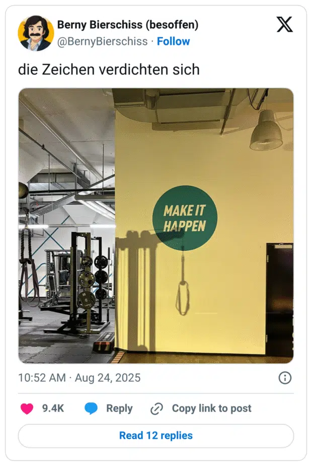 Fitnessstudio. An einer gelben Wand steht groß „MAKE IT HAPPEN“. Daneben wirft ein herabhängender Trainingsgriff einen langen Schatten, der wie eine Schlaufe wirkt – unglücklicher Kontrast zum Motivationsspruch.
