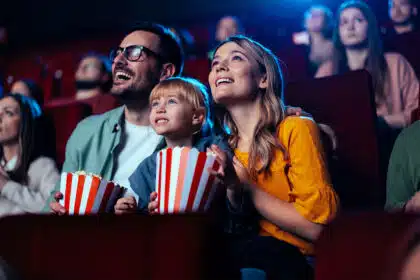 Familie ist zusammen im Kino und schaut mit Popcorn in den Händen einen Kinofilm.