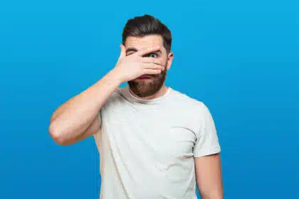 Ein Mann hält sich ängstlich die Hand vor die Augen.