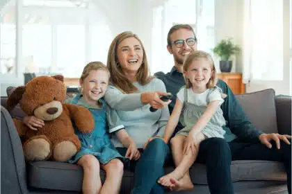 Glückliche Familie sitzt zusammen daheim auf dem Sofa.