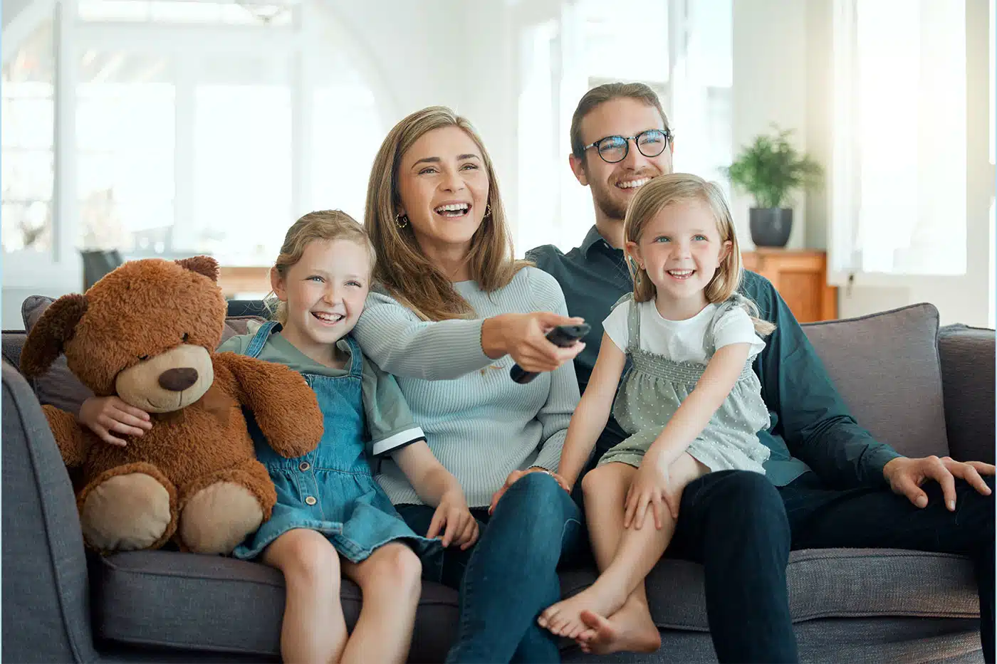 Glückliche Familie sitzt zusammen daheim auf dem Sofa.