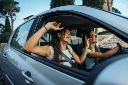 Zwei junge Frauen sitzen im Auto und hören zusammen Musik, während sie fahren.