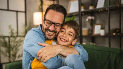 Papa lacht herzlich und umarmt seinen Sohn.