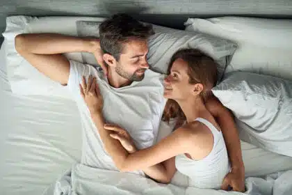 Ein Mann und eine Frau liegen gemeinsam Arm in Arm im Bett und lächeln sich an.