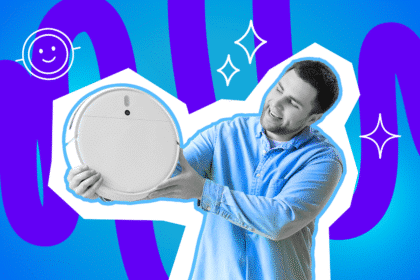 Ein Mann hält lächelnd einen Saugroboter in den Händen, als würde er ihn stolz präsentieren.