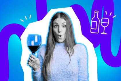 Frau hält überrascht ein Glas Rotwein in der Hand.