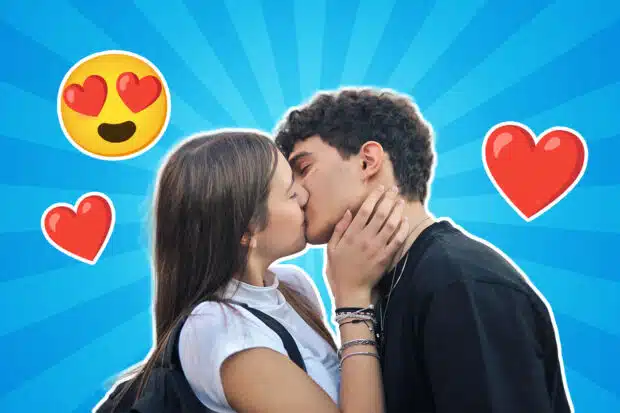 Ein junges Teenager Paar küsst sich vor einem blauen Hintergrund mit Strahlenmuster; um sie herum sind rote Herzen und ein Emoji mit Herzaugen zu sehen.
