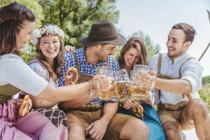 Eine Gruppe von Menschen auf dem Okroberfest stoßen mit ihren Bierkrügen an und lachen herzlich.