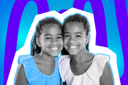 Zwei lächelnde Mädchen stehen eng beieinander, wirken wie Zwillinge und tragen sommerliche Oberteile.