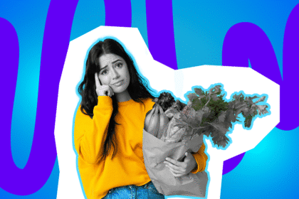 Junge Frau im gelben Pullover hält eine volle Papiertüte mit Lebensmitteln und blickt besorgt in die Kamera.