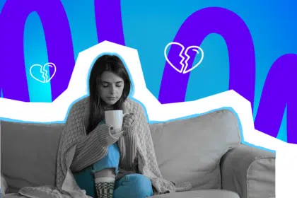 Eine junge Frau sitzt eingekuschelt auf dem Sofa, hält eine Tasse in den Händen und wirkt nachdenklich vor einem grafischen Hintergrund mit gebrochenen Herzen.