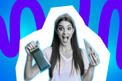 Eine überraschte Frau hält vor blau-lila Hintergrund eine Käsereibe und ein Stück Käse in den Händen.Eine überraschte Frau hält vor blau-lila Hintergrund eine Käsereibe und ein Stück Käse in den Händen.