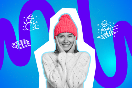 Eine fröhliche Frau in Winterkleidung: mit roter Strickmütze und kuscheligem Pullover, die Hände an den Wangen.