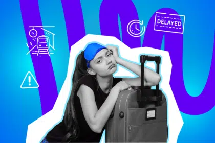 Eine erschöpfte junge Frau lehnt mit genervtem Blick an ihrem Koffer und wartet wegen einer verspäteten Zugverbindung.