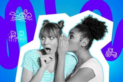 Zwei junge Frauen stehen eng beieinander. Die eine beugt sich zur anderen und flüstert ihr etwas ins Ohr, die Hand schützend davor gehalten.