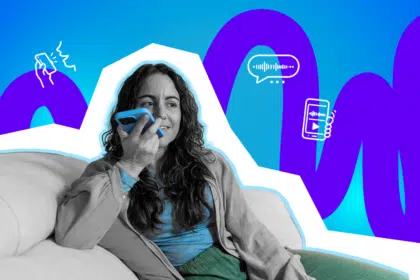 Eine Frau sitzt entspannt auf dem Sofa und hält ihr Smartphone nah an den Mund, als würde sie gerade eine Sprachnachricht aufnehmen oder anhören.