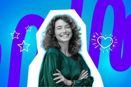 Selbstbewusste Frau strahlt mit verschränkten Armen in die Kamera.