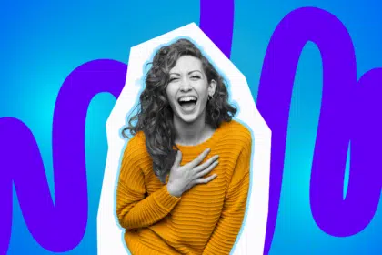 Eine Frau hält sich vor lachen die Brust.