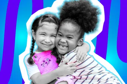 Eine herzerwärmende Collage zum Thema emotionale Unterstützung und Freundschaft: Zwei lachende Mädchen in Schwarz-Weiß umarmen sich innig und strahlen in die Kamera. Das linke Mädchen hat geflochtene Zöpfe und trägt eine leuchtend pinke Latzhose mit Blumenstickerei, das rechte Mädchen trägt das Haar hochgesteckt und ein hell gestreiftes Oberteil. Das fröhliche Motiv vor einem blau-violetten Wellen-Hintergrund visualisiert geteilte Freude und starken Zusammenhalt.