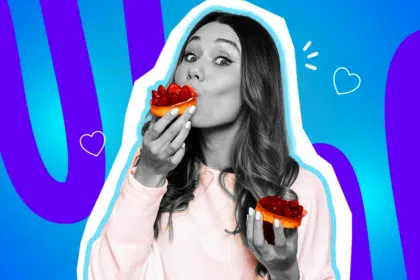 Humorvolle Collage zum Thema Dessertliebe und Naschkatzen: Eine völlig begeisterte Frau in Schwarz-Weiß mit weit aufgerissenen Augen beißt genüsslich in ein kleines, fruchtiges Erdbeertörtchen in leuchtenden Farben. In der anderen Hand hält sie vorsichtshalber direkt das nächste Törtchen parat. Sie trägt einen zartrosa Pullover. Weiße Herz-Icons und das Pop-Art-Motiv vor einem markanten blau-violetten Wellen-Hintergrund visualisieren pointiert die unbändige Vorfreude, die pure Lust auf Süßes und die absolute Gewissheit, dass für den Nachtisch immer noch ein zweiter Magen bereitsteht.