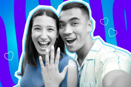Fröhliche Collage zum Thema Heiratsantrag, Verlobung und große Liebe: Im Zentrum macht ein überglückliches Paar, dessen Gesichter und Haut in Schwarz-Weiß gehalten sind, strahlend lachend ein Selfie. Die Frau auf der linken Seite hält ihre Hand jubelnd in die Kamera und präsentiert stolz einen leuchtend rot-orangen Verlobungsring. Sie trägt ein kräftig blaues Oberteil, während ihr Partner rechts ein hellblau gestreiftes Hemd trägt. Diese farbigen Elemente treten extrem stark hervor. Weiße Herz-Icons sowie das Pop-Art-Motiv vor einem markanten blau-violetten Wellen-Hintergrund visualisieren pointiert die pure Freude über das langersehnte "Ja" und das unbeschwerte Glück frisch Verlobter.