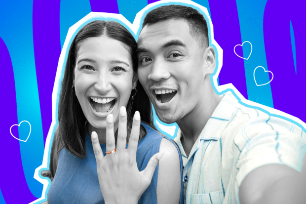 Fröhliche Collage zum Thema Heiratsantrag, Verlobung und große Liebe: Im Zentrum macht ein überglückliches Paar, dessen Gesichter und Haut in Schwarz-Weiß gehalten sind, strahlend lachend ein Selfie. Die Frau auf der linken Seite hält ihre Hand jubelnd in die Kamera und präsentiert stolz einen leuchtend rot-orangen Verlobungsring. Sie trägt ein kräftig blaues Oberteil, während ihr Partner rechts ein hellblau gestreiftes Hemd trägt. Diese farbigen Elemente treten extrem stark hervor. Weiße Herz-Icons sowie das Pop-Art-Motiv vor einem markanten blau-violetten Wellen-Hintergrund visualisieren pointiert die pure Freude über das langersehnte "Ja" und das unbeschwerte Glück frisch Verlobter.