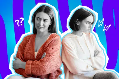 Ausdrucksstarke Collage zum Thema Ghosting in Freundschaften, Kontaktabbruch und schmerzhafte Funkstille: Auf der linken Seite sitzt eine junge Frau, deren Gesicht und Hände in Schwarz-Weiß gehalten sind, mit verschränkten Armen. Sie blickt fragend, traurig und sichtlich enttäuscht zur Seite. Ihre dicke, leuchtend orangefarbene Strickjacke tritt farblich extrem stark hervor. Rücken an Rücken mit ihr sitzt auf der rechten Seite eine weitere junge Frau, deren Gesicht und Hände ebenfalls in Schwarz-Weiß gehalten sind. Auch sie hat die Arme verschränkt, schaut jedoch stur und verärgert in die entgegengesetzte Richtung. Sie trägt einen weißen Kapuzenpullover. Weiße Fragezeichen-Icons über der linken und Blitz-Icons über der rechten Frau sowie das Pop-Art-Motiv vor einem markanten blau-violetten Wellen-Hintergrund visualisieren pointiert die emotionale Distanz, die quälende Ungewissheit und den bitteren Schmerz, wenn man von einer ehemals engen Freundin plötzlich und völlig ohne Erklärung geghostet wird